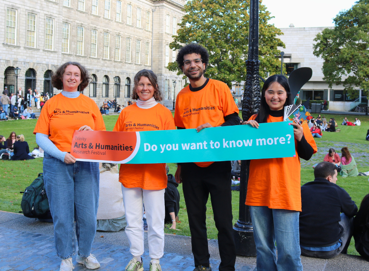 Four Early Career Researchers in orange festival t shirts holding a sign thats reads
