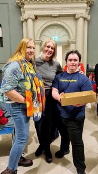 two woman and a man holding a box