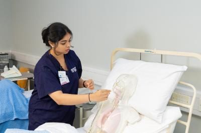 students treating a dummy patient in bed