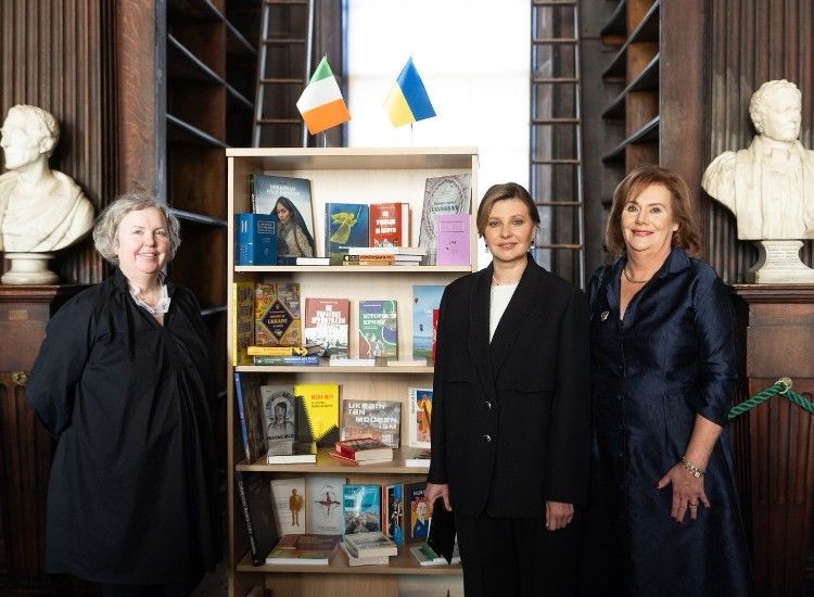 Three women pose in front of a bookshelf