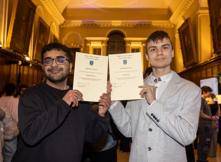 Two male students pose with certificates