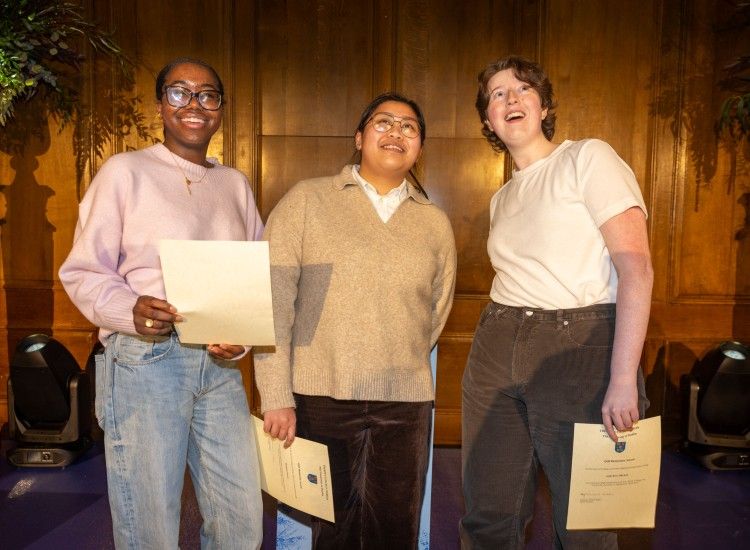Three young women pose with certificates