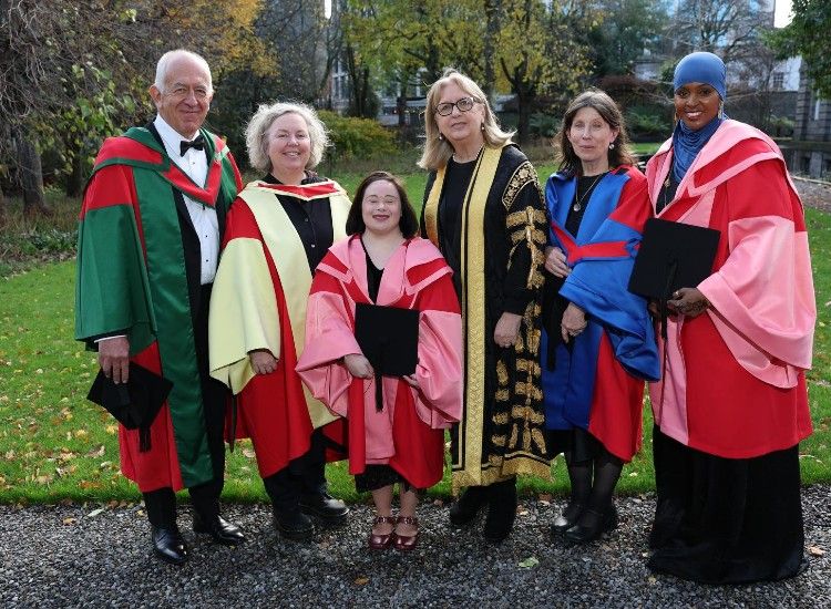 Six people pose in academic robes