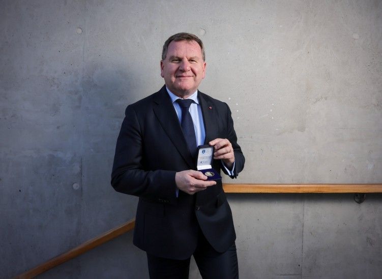 Man in suit poses with medal