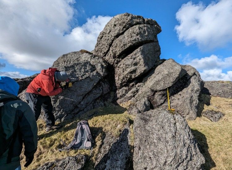 Researcher in red jacket on a rocky outcrop