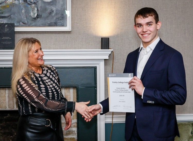 A woman congratulates a young man with a certificate