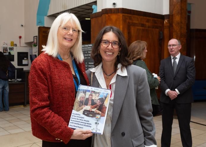 Two women pose with booklet