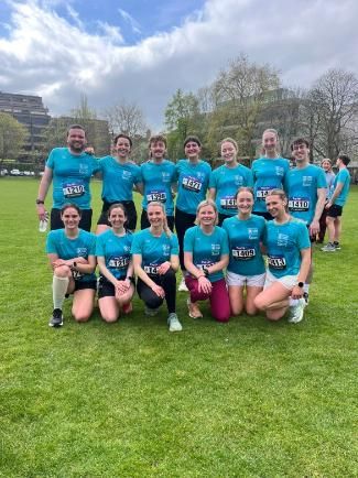 13 members of staff and students pose on the green in TCD following their run