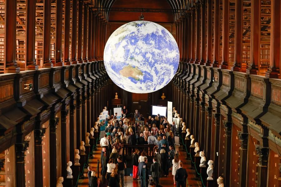 Photo taken from the balcony of the Trinity Long Room, looking down on the attendees of the COMPET event. Above them, Gaia, an inflated globe of the earth, hangs above them.