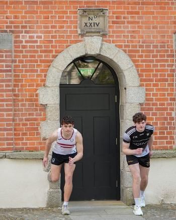Two runners waiting to start the 2026 'Chariots of Fire' run at Trinity with their back foot against a Ruebrick door