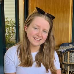 Student with light hair smiling, she has sunglasses sitting on the top of her head