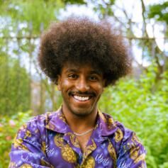 Headshot of student smiling, they are wearing a purple patterned shirt