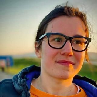 Student with brown hair and glasses smiling
