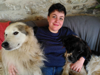 Student with short dark hair smiling. There are two dogs, one either side.