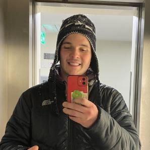 student taking a selfie, he is wearing a hat and smiling