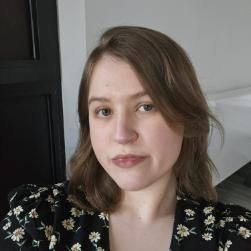 student with light brown hair smiling for photo, wearing a patterned top